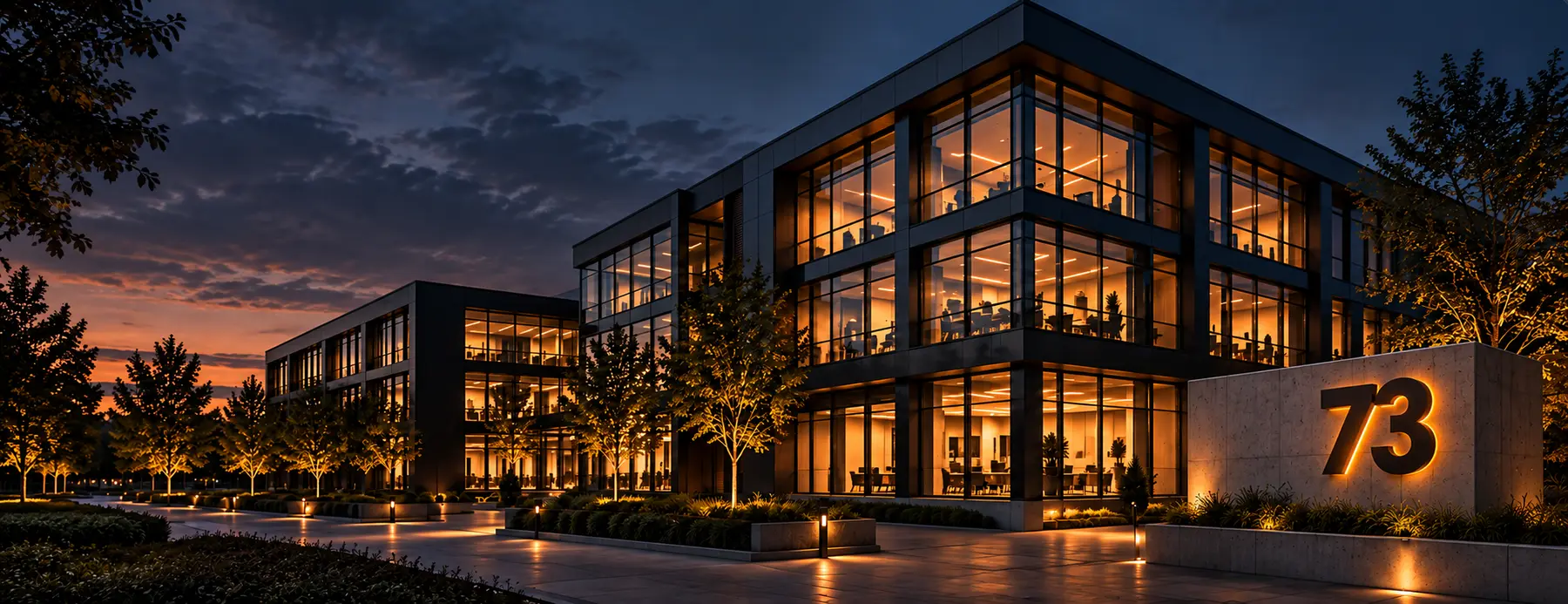 Modern technology-ready building at dusk with the number 73 mounted on a concrete entrance monument